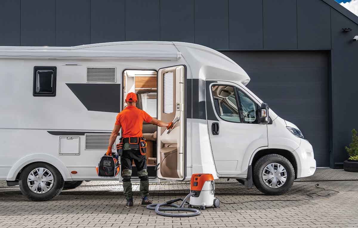 Technician cleaning and servicing a camper van.