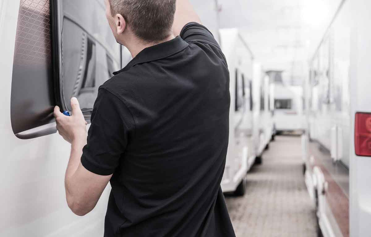 Person inspecting camper window in storage facility.