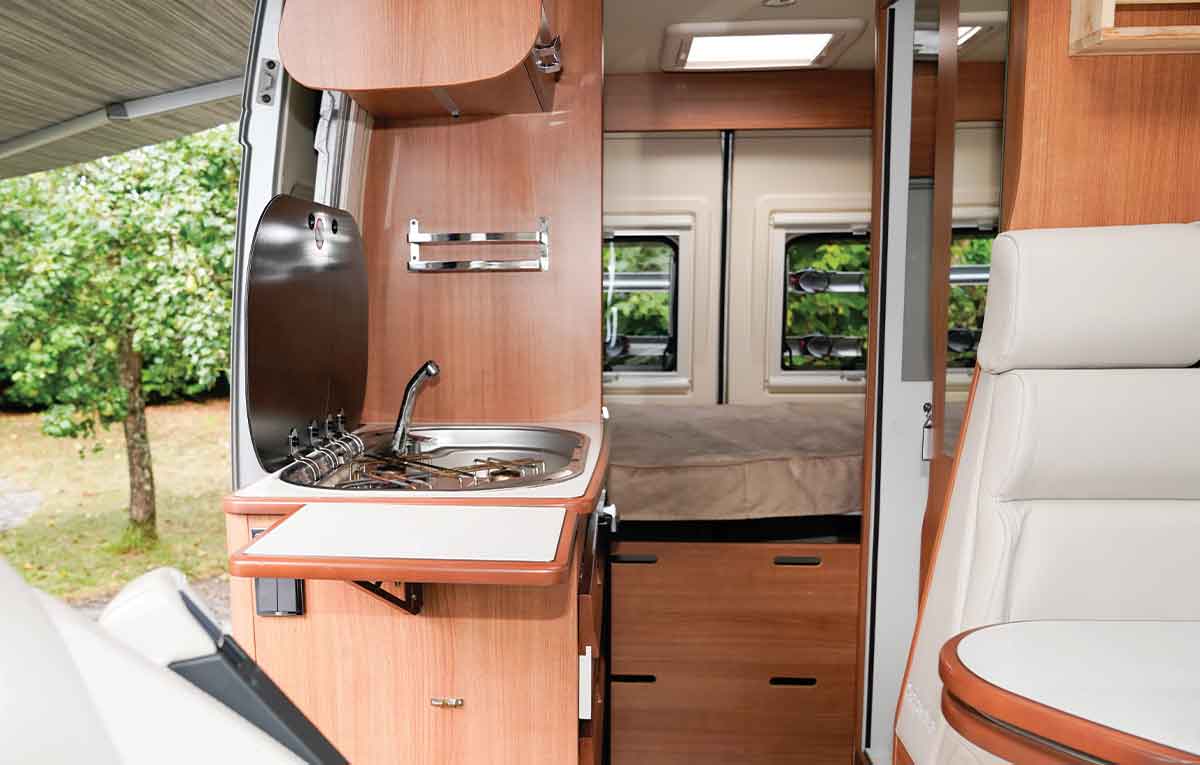 Modern RV interior with kitchenette and seating area.
