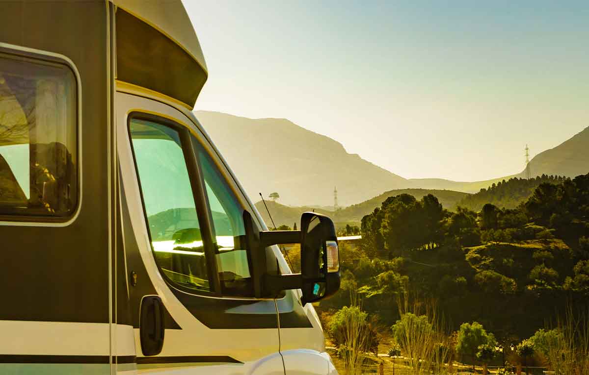 RV parked with scenic mountain view at sunset.
